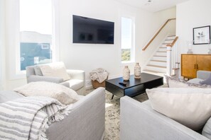 A living room with a sofa, a coffee table, and a TV mounted on the wall.
