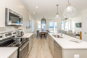 A modern kitchen with a central island, stainless steel appliances, and pendant lighting.