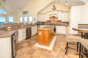 A spacious kitchen with a central island, white cabinetry, and a view of the ocean. - Island Life - Amazing Oceanfront 9 BR Home with Pool, Theatre Room & More! (North Topsail Beach)