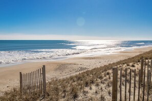 A beach with a wooden fence, sandy shore, and ocean waves.
