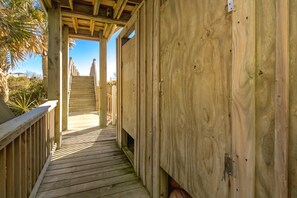 A wooden deck leading to a covered area with a view of the outdoors. - Island Life - Amazing Oceanfront 9 BR Home with Pool, Theatre Room & More! (North Topsail Beach)