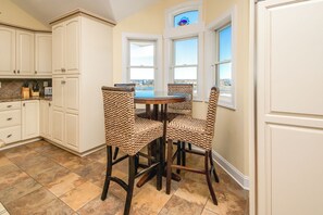 Une cuisine avec des meubles blancs, une table ronde et des chaises en osier.