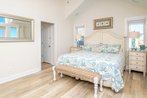A bedroom with a large bed, a bench, a nightstand, and a framed picture on the wall. - Island Life - Amazing Oceanfront 9 BR Home with Pool, Theatre Room & More! (North Topsail Beach)