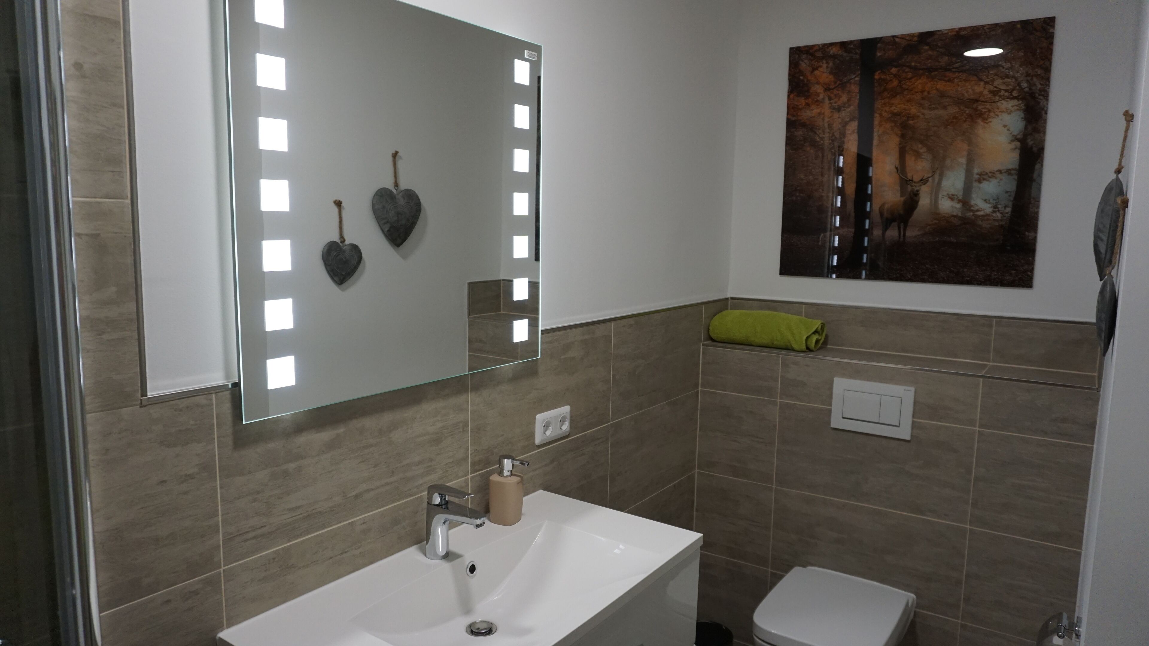 Ein Badezimmer mit Waschbecken, Spiegel und einem Gemälde einer Waldszene.