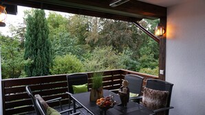 Une terrasse extérieure avec une table, des chaises et une vue sur une forêt.