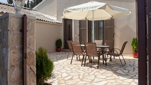 An outdoor patio with a stone floor, a table with chairs, and a large umbrella.