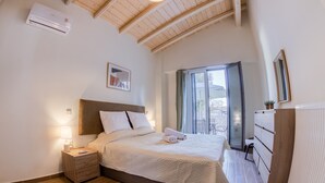 A bedroom with a large bed, a nightstand, a dresser, and a window with a view.