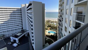 Un hôtel de grande hauteur doté de nombreux balcons donnant sur une plage et une piscine.