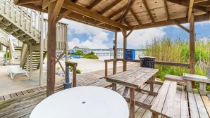 Une terrasse en bois avec des tables de pique-nique et une table blanche au premier plan.