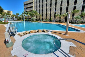 A swimming pool with a hot tub, surrounded by palm trees and a modern building with balconies. - FREE Beach Service & Perks! Emerald Beach 732 Pool, Hot Tub, Starbucks, Gym! (Panama City Beach)