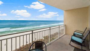 A balcony with a view of the ocean, a chair, and a table. - FREE Beach Service & Perks! Emerald Beach 732 Pool, Hot Tub, Starbucks, Gym! (Panama City Beach)