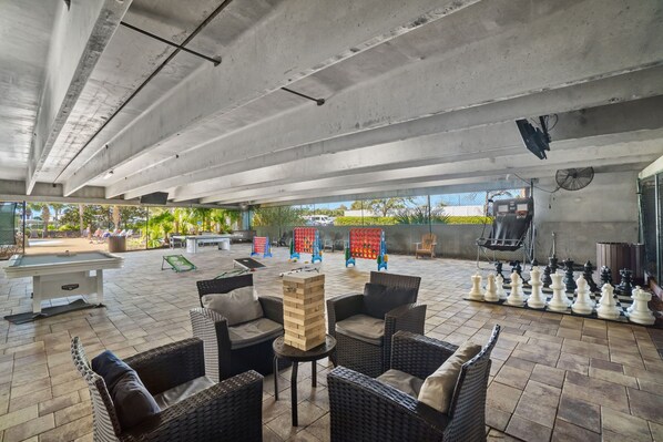 An outdoor patio area with wicker furniture, a pool table, and a chessboard.