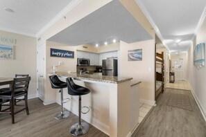 A modern kitchen with a central island, bar stools, and a dining area with a table and chairs.