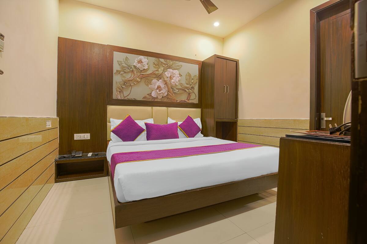 Un dormitorio ordenado con una cama grande, cabecera de madera y un cuadro decorativo con flores encima.
