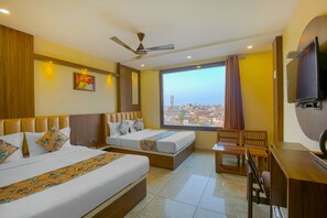 Habitación de hotel con dos camas, un escritorio, una silla, un televisor y vistas a la ciudad.