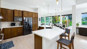 A modern kitchen with wooden cabinets, stainless steel appliances, a large island, and pendant lighting. - Incredible Views From This 4 Bedroom Pool Home With Office and Sofa Sleeper (La Quinta)