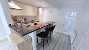 Una cocina moderna con gabinetes blancos, encimera de granito y una isla integrada con taburetes de bar.