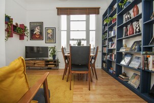 Una sala de estar con televisor, muebles de madera, una estantería y una ventana.