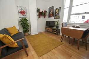Una sala de estar con sofá, mesa de centro, televisor y mesa de comedor.