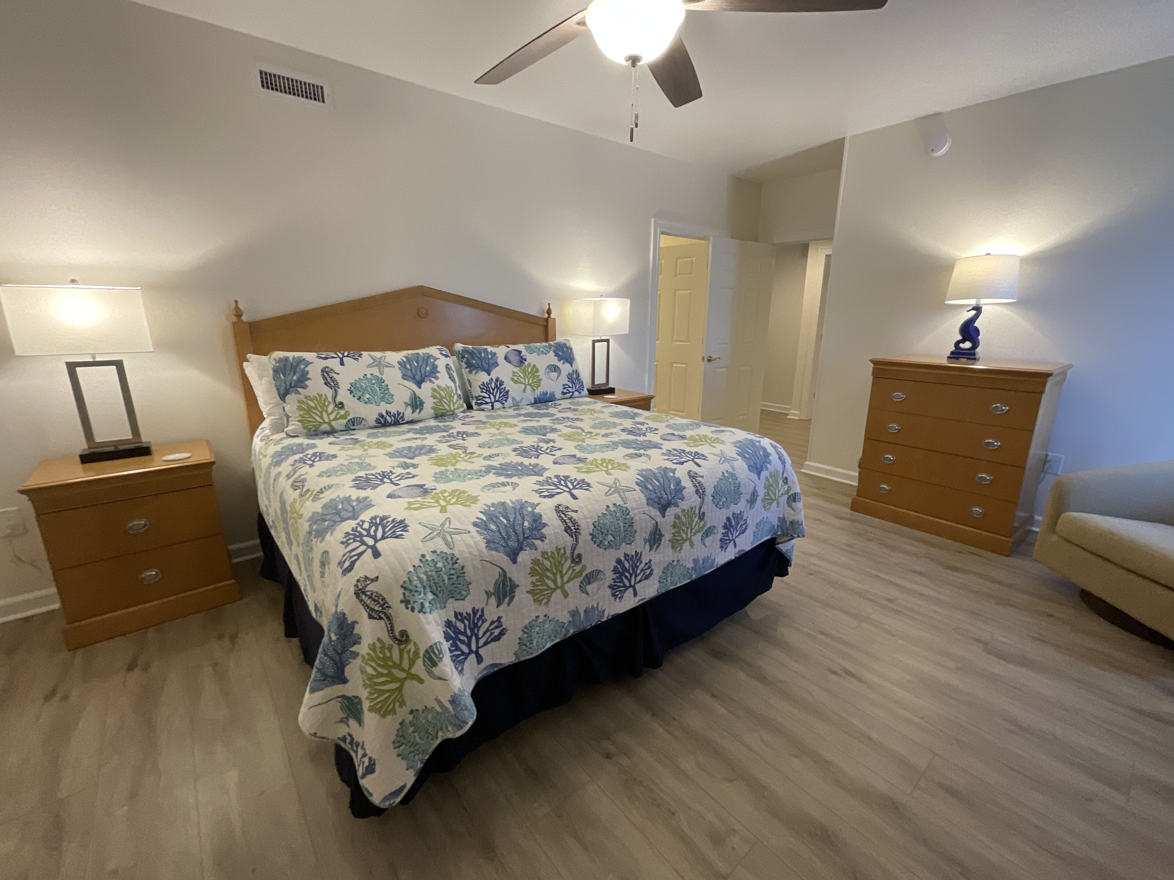 A bedroom with a bed, two nightstands, a dresser, and a ceiling fan.