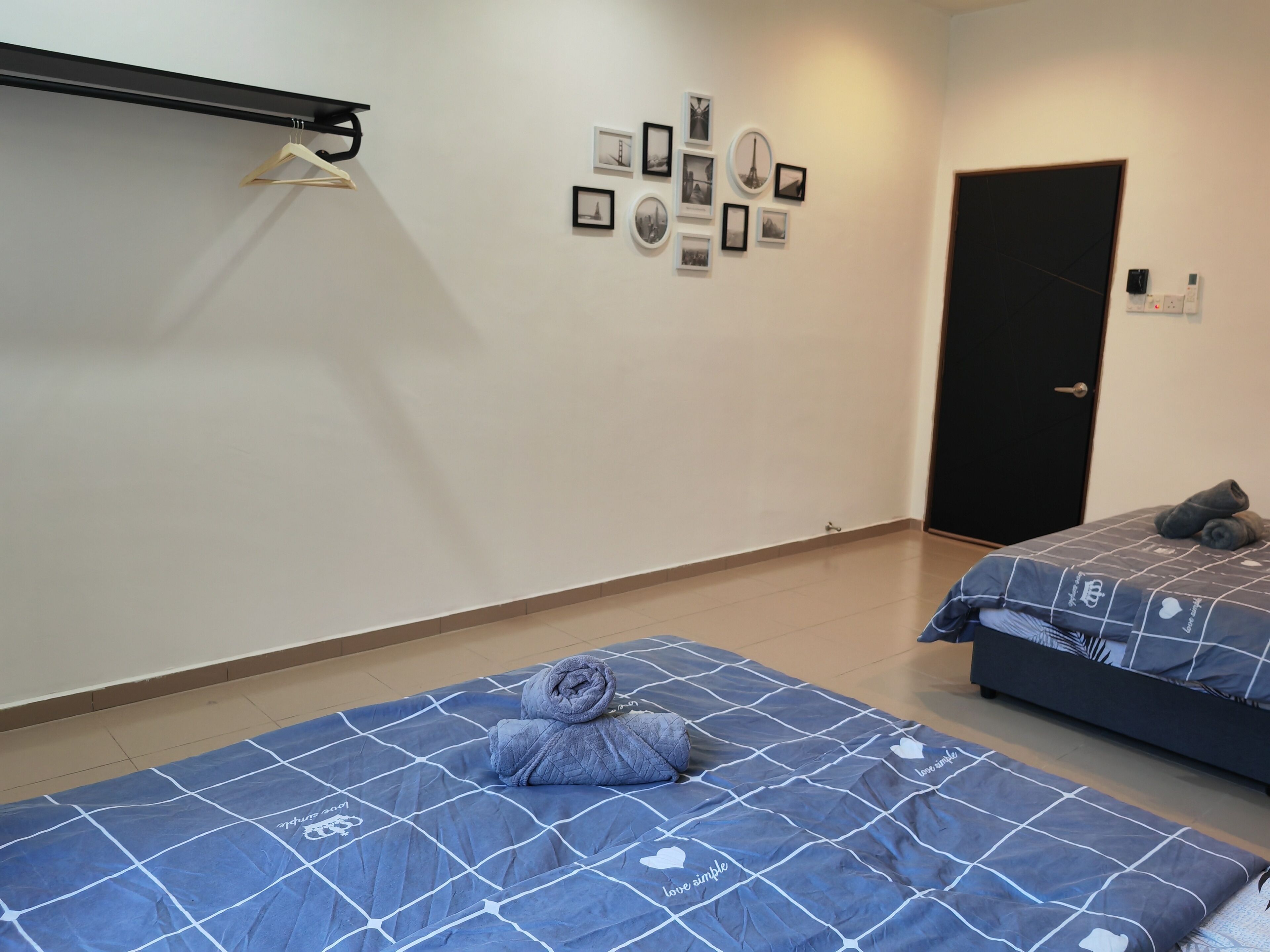 Una camera d'albergo con due letti, un armadio, una parete decorata con quadri e una porta con serratura.