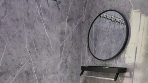A bathroom with a white pedestal sink, a black faucet, and a round mirror mounted on a black shelf. - Padang Serai Deluxe Roomstay (Padang Serai)