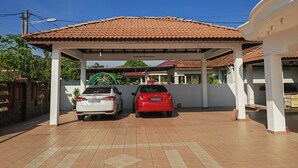 A covered parking area with two cars parked under a tiled roof. - Padang Serai Deluxe Roomstay (Padang Serai)