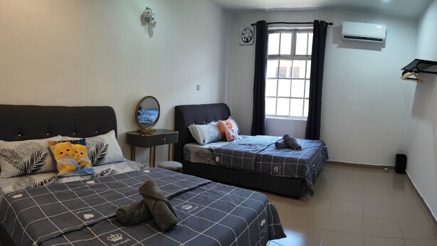 A bedroom with two beds, a window with curtains, an air conditioning unit, and a wall-mounted shelf with a few items. - Padang Serai Deluxe Roomstay (Padang Serai)