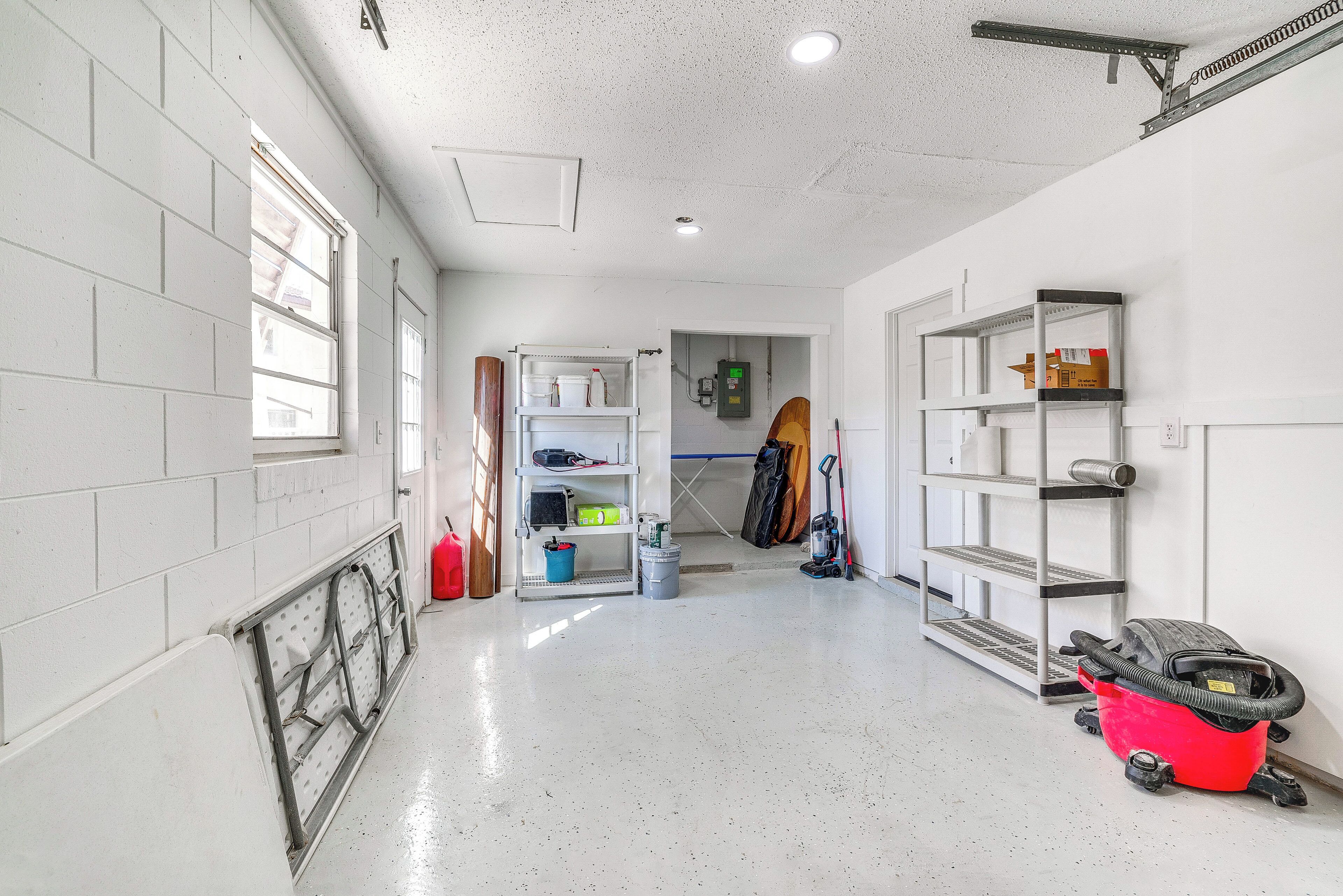 A clean, well-lit hallway with white walls, a metal rack, and shelves with various items.