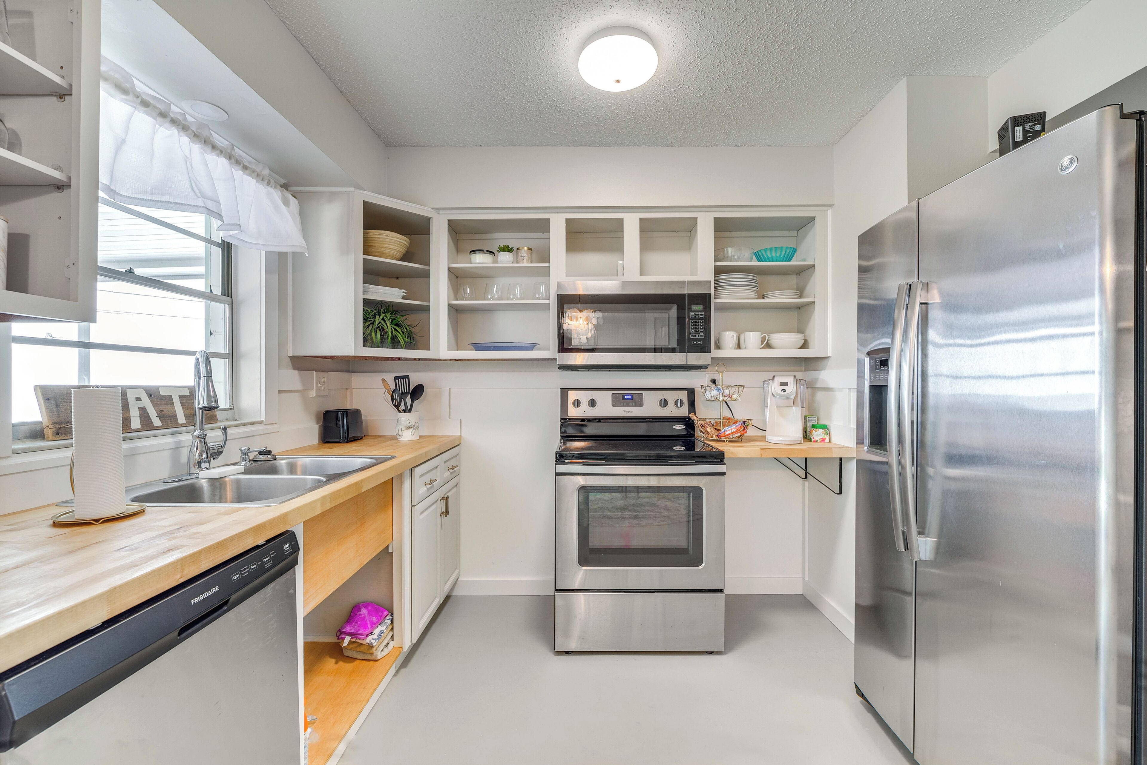 A modern kitchen with stainless steel appliances, white cabinetry, and a built-in microwave.