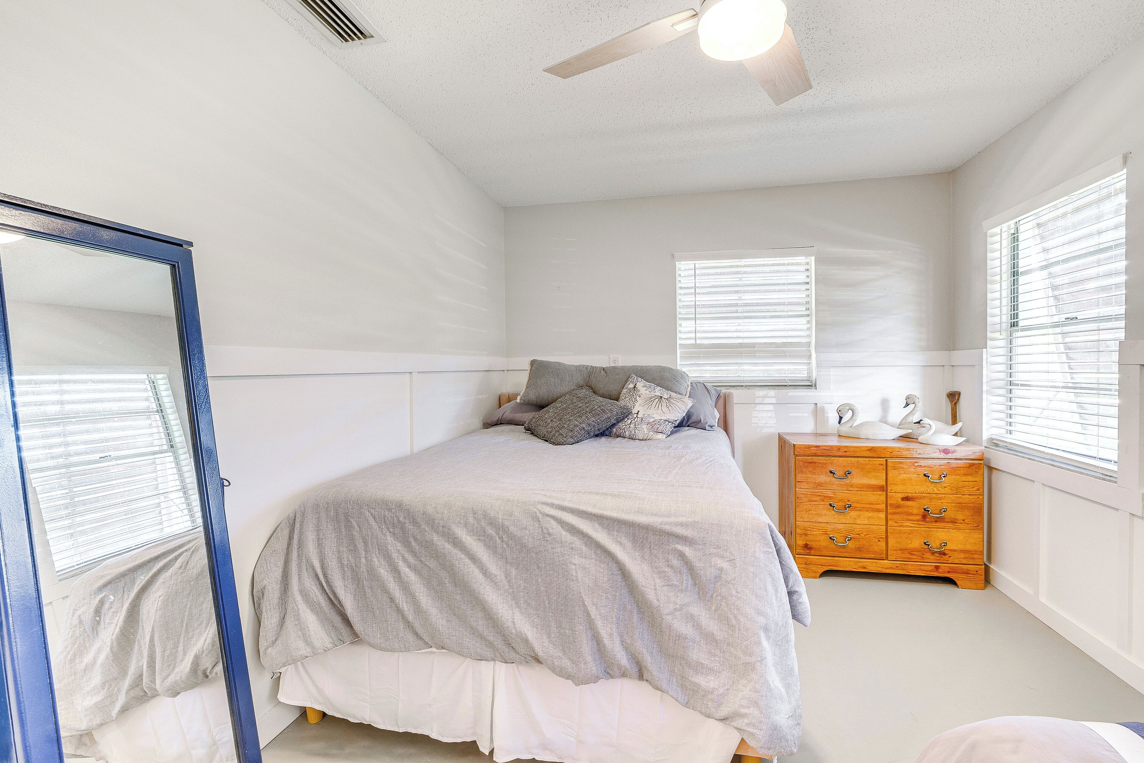 A bedroom with a bed, dresser, and a mirror.