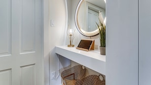 A bathroom with a white vanity, a round mirror, a tablet, a potted plant, and wicker baskets. - 2 Mi to Downtown Denver: Stylish Gem w/ Fireplace! (Denver)
