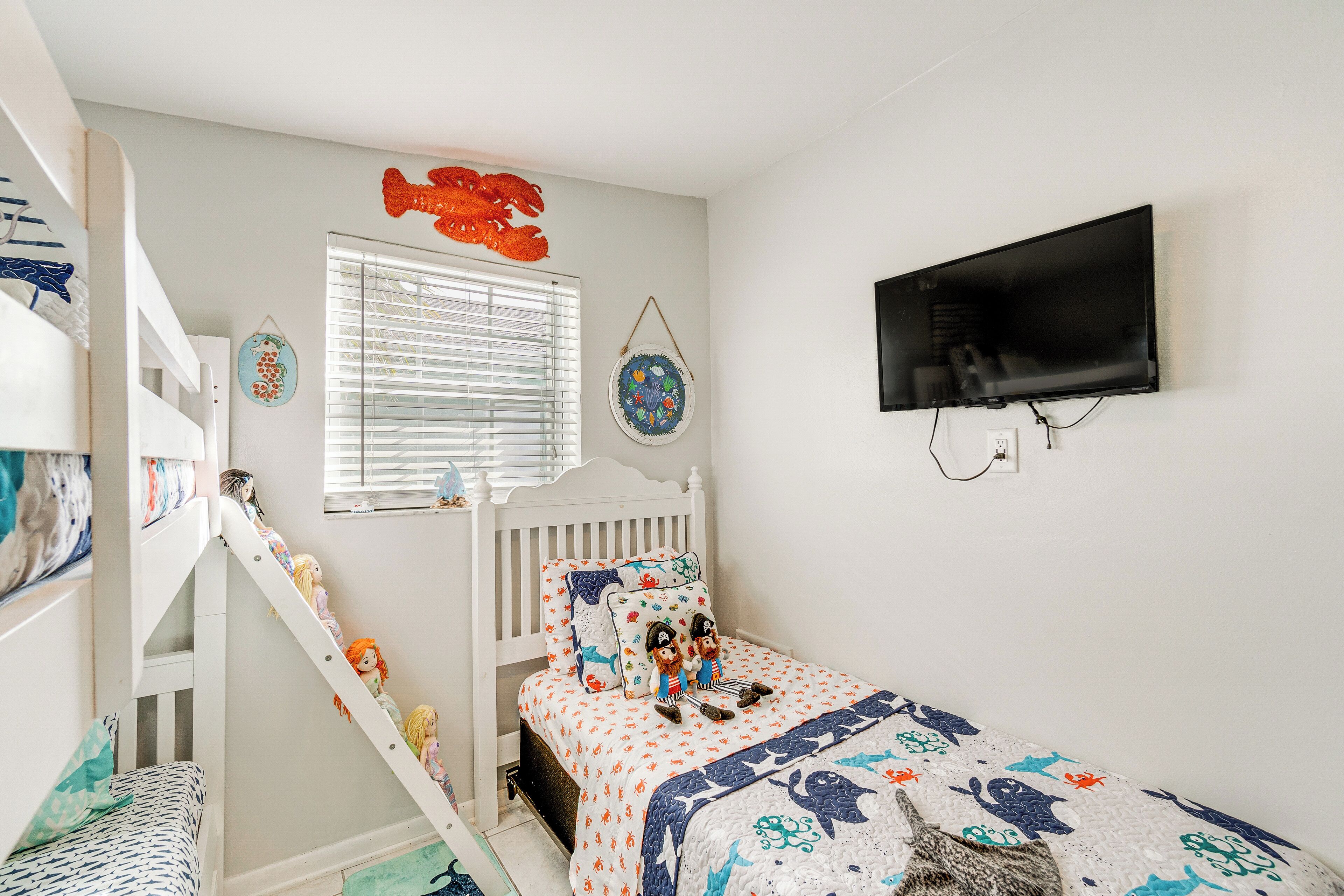 A child's bedroom with bunk beds, a TV, and decorative wall hangings.