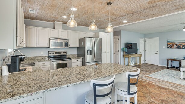 A modern kitchen with granite countertops, stainless steel appliances, and pendant lighting. - Pet-friendly Beaufort Home w/ Private Yard (Beaufort)