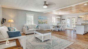 A spacious living room with a large coffee table, a sofa, and a dining area with a chandelier. - Pet-friendly Beaufort Home w/ Private Yard (Beaufort)
