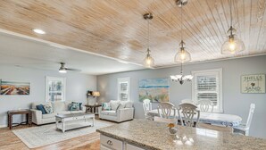 A spacious living room with a large wooden ceiling, a dining area with white furniture, and a kitchen with granite countertops. - Pet-friendly Beaufort Home w/ Private Yard (Beaufort)