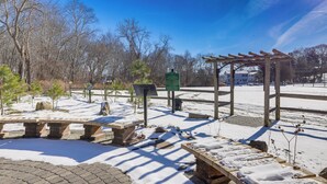 A snow-covered outdoor area with benches, a wooden pergola, and a signboard.