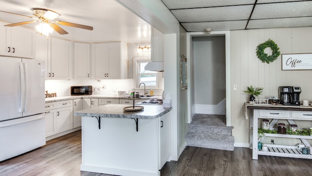 A modern kitchen with white cabinetry, a central island, and a ceiling fan. - Family-friendly Altoona Abode w/ Spacious Patio! (Altoona)