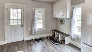 A kitchen with white cabinets, a bench, and a refrigerator. - Family-friendly Altoona Abode w/ Spacious Patio! (Altoona)