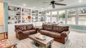 A living room with two brown leather sofas, a wooden coffee table, and a bookshelf filled with decorative items. - St Simons Island Townhome w/ Balcony + Ocean View! (St. Simons Island)