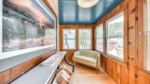 Een kamer met houten wanden, grote ramen, een bank en een boekenkast.