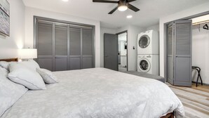 A bedroom with a bed, a ceiling fan, and a washing machine in the adjacent room. - Central Cedar City Apartment: Walk to Suu! (Cedar City)