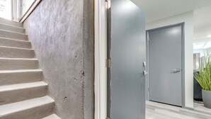 A staircase leading to a room with a grey door and a potted plant in the corner. - Central Cedar City Apartment: Walk to Suu! (Cedar City)