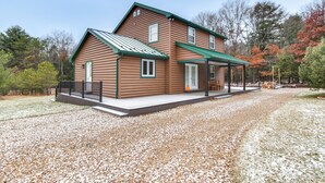 A two-story log cabin with a covered porch and a gravel driveway. - Houtzdale Home w/ Shuffleboard & Pickleball! (Houtzdale)