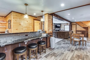 A kitchen with wooden walls, a black countertop, and bar stools.