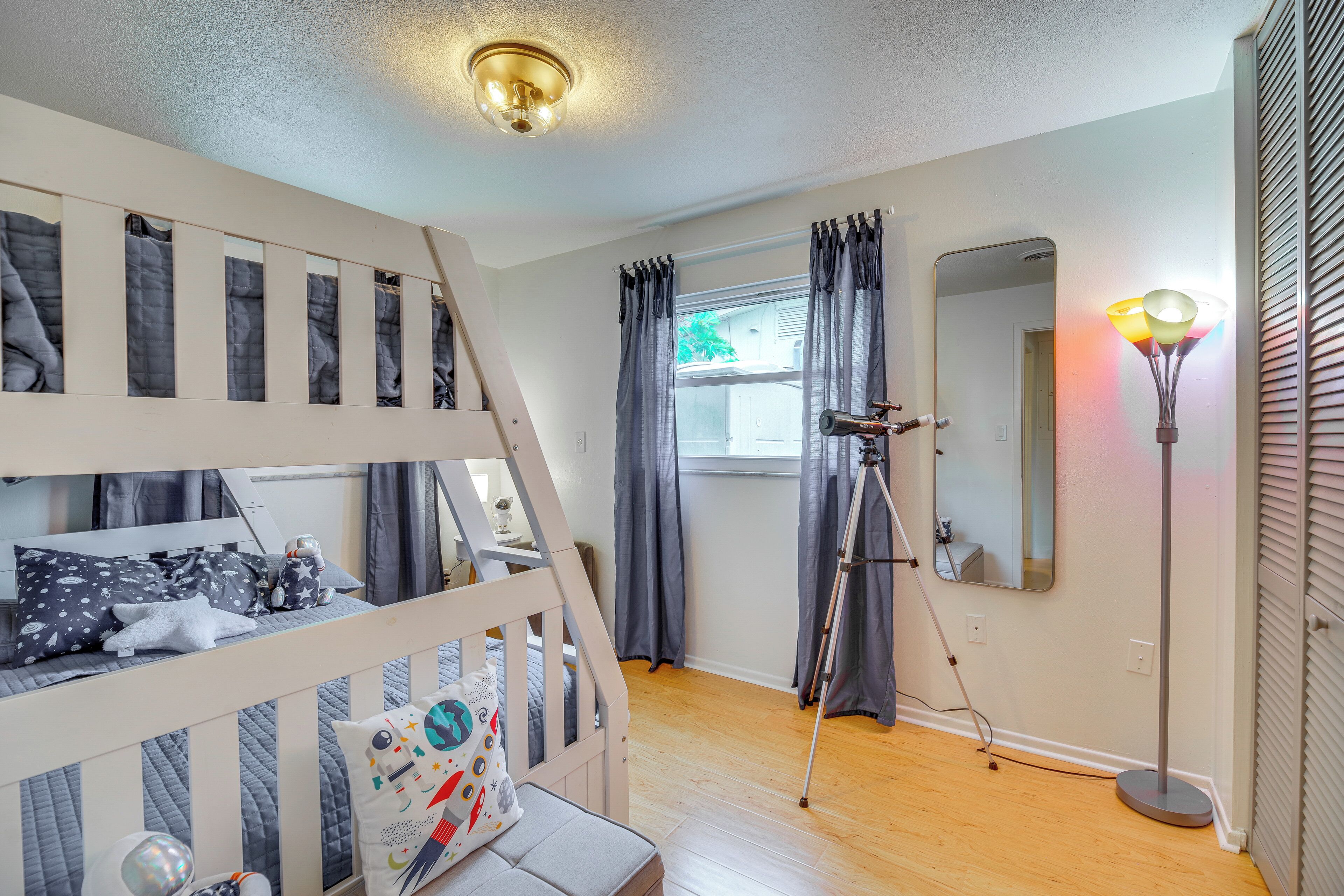 Un lit superposé pour enfant, avec un télescope, une lampe sur pied et un miroir accroché au mur.