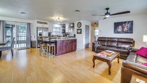 A spacious living area with a brown leather sofa, wooden coffee table, and a kitchen with a central island.
