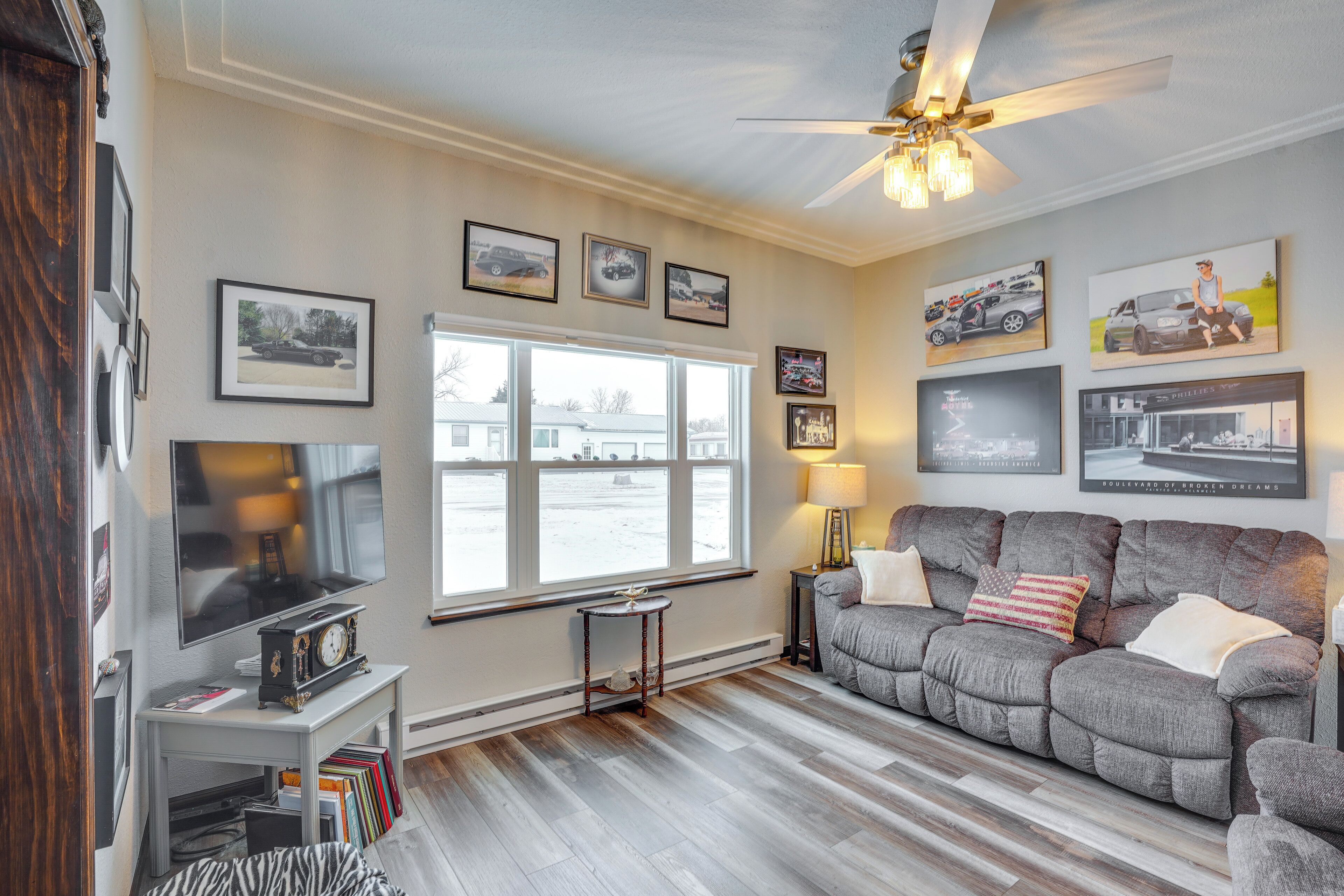 A living room with a large window, a ceiling fan, and a gray sofa.