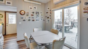 Un comedor con mesa y sillas, un reloj de pared y un ventanal con vistas al exterior.