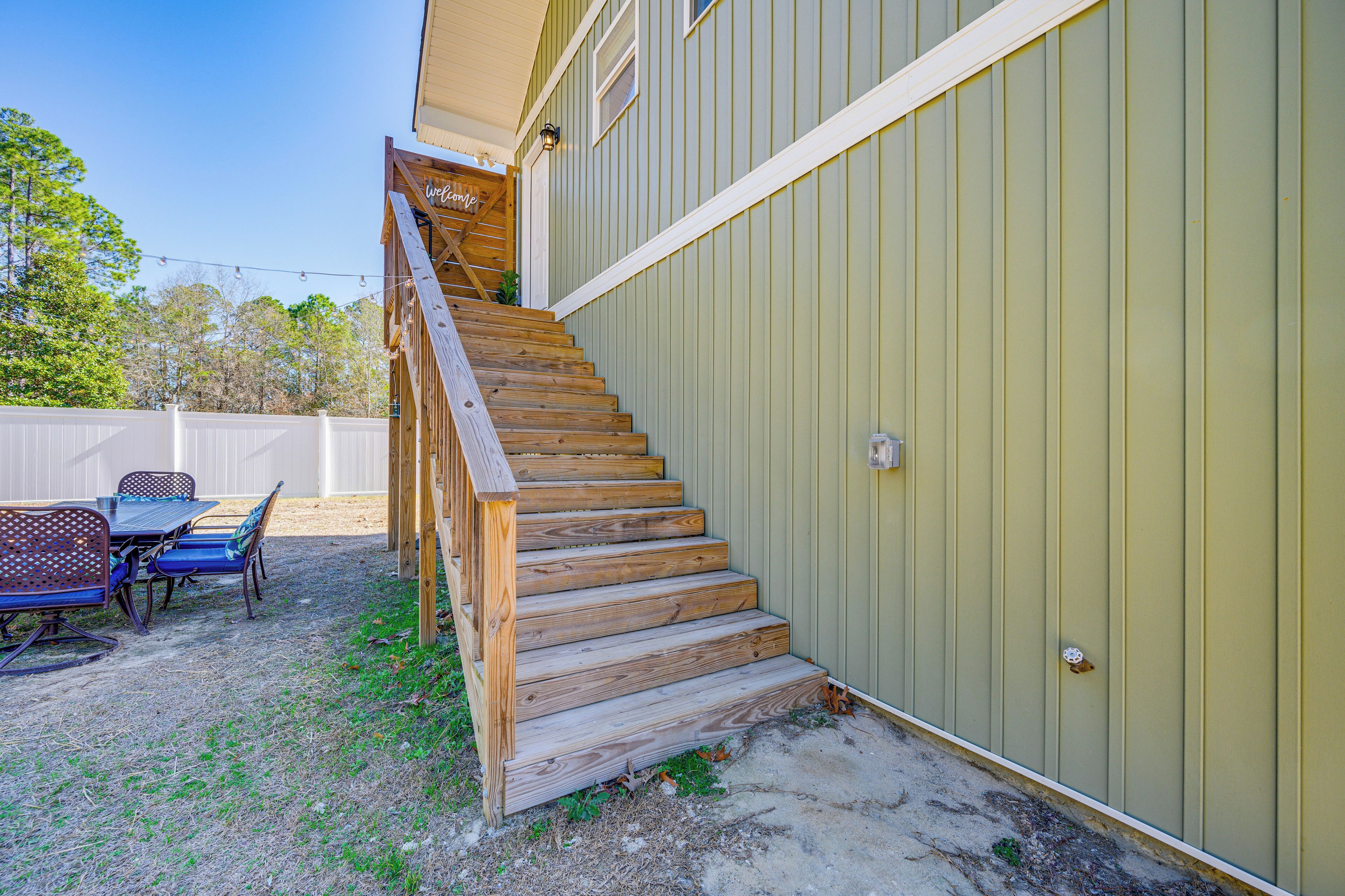 A wooden staircase leading to a covered outdoor area with a table and chairs.